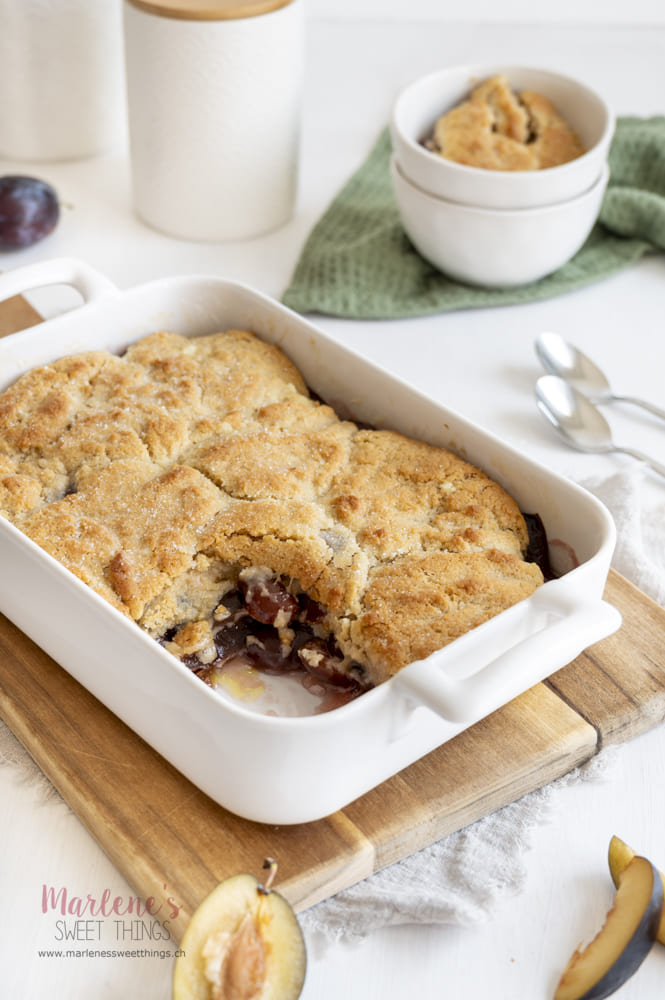 Frisch gebackener Zwetschgen-Cobbler mit knuspriger Teigdecke in einer weißen Auflaufform