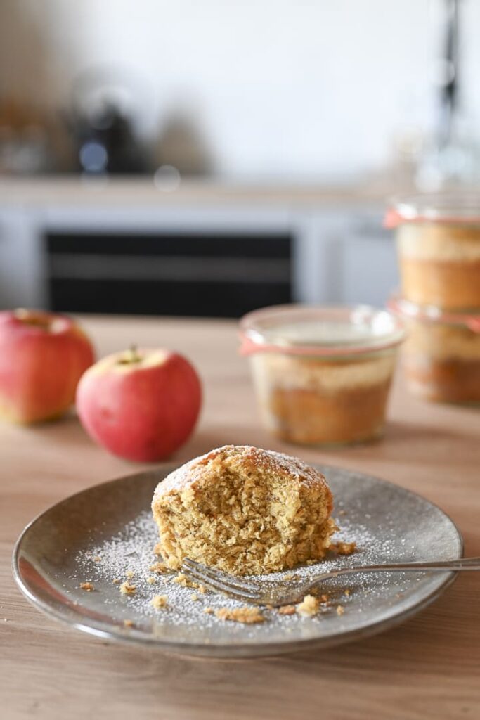 Apfel-Nuss-Kuchen im Glas – saftiger Kuchen auf Teller mit Äpfeln und eingekochten Gläsern im Hintergrund